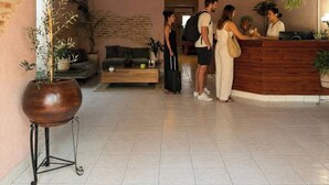 A reception area with a wooden reception desk, a seating area with a sofa and coffee table, and a potted plant. - PUNTO AMERICANA HOSTAL (Guadalajara)
