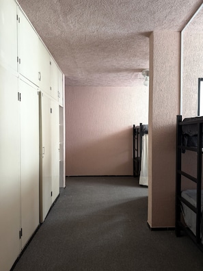 Ein Korridor mit Schließfächern, Etagenbetten und einer strukturierten Wand.
