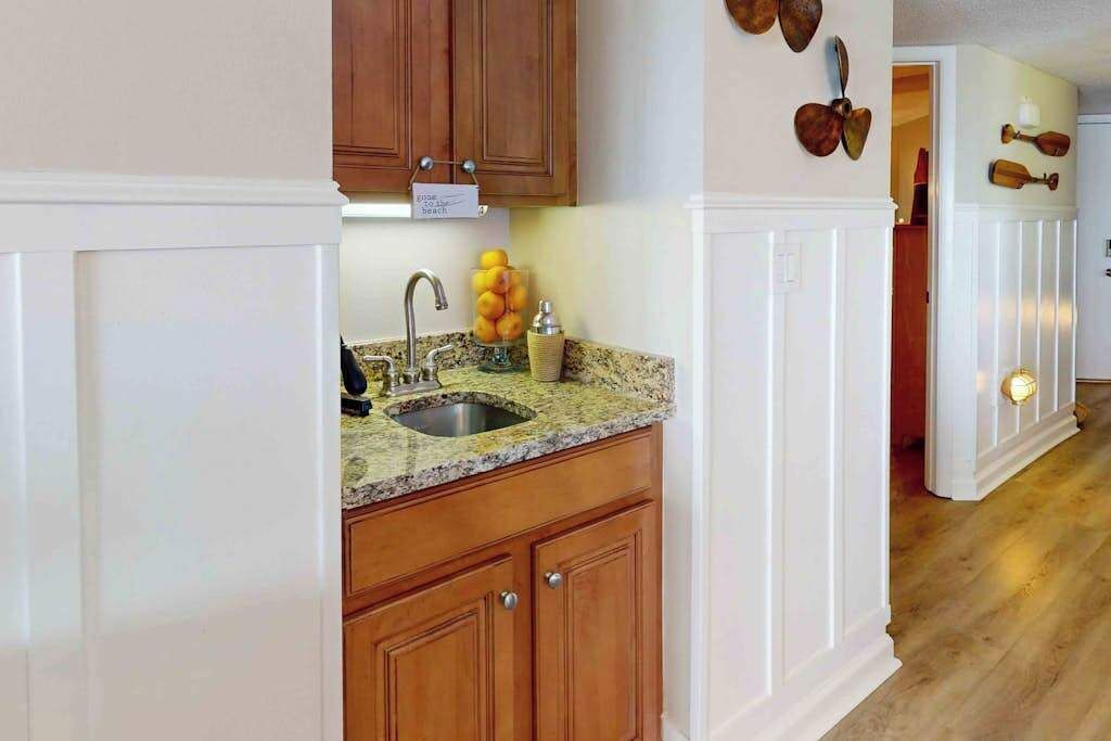 A kitchen with wooden cabinets, a granite countertop, a sink, and a wall-mounted light fixture.