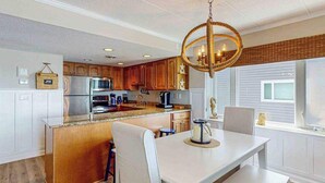 A modern kitchen with wooden cabinets, a central island, and a chandelier. - Luxury waterfront condo w/water views from balcony, shared pool, AC & free WiFi (Ocean City)