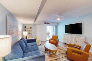 A living room with a sofa, armchairs, a coffee table, a TV, and a sign that reads 'BEACH'. - Bluewater East 202S (Ocean City)