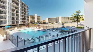 Ett hotell med en swimmingpool, flera balkonger och utsikt över gatan.