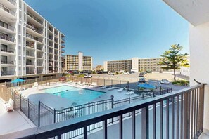 A hotel with a swimming pool, multiple balconies, and a view of the street. - Bluewater East 202S (Ocean City)