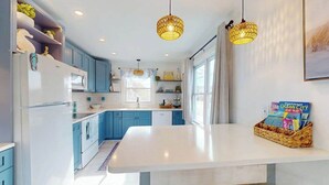 A modern kitchen with blue cabinets, a white island, and pendant lighting. - Robin View 2 (Ocean City)