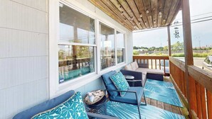 A covered porch with a wooden ceiling, large windows, and outdoor seating with patterned cushions. - Robin View 2 (Ocean City)