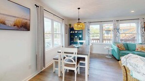 A dining area with a table and chairs, a hanging light fixture, and a view of the outside. - Robin View 2 (Ocean City)