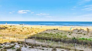Ein Strand mit einer Holzumzäunung, Sanddünen und dem Meer im Hintergrund.