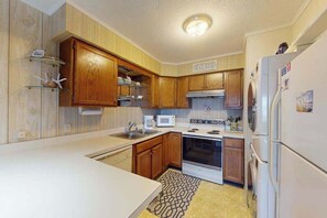 Una cocina con armarios de madera, microondas, horno y refrigerador.