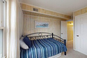 Un dormitorio con una cama, un cuadro en la pared y una puerta.