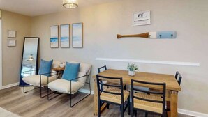 Ein modernes Wohnzimmer mit einer Couch, einem Esstisch mit Stühlen, einem Holzbatterflug und einem 'WIFI'-Schild an der Wand.