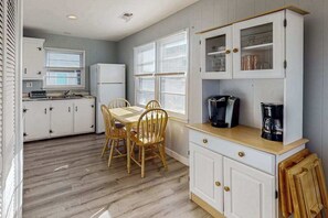 A kitchen with a dining table, chairs, a refrigerator, and a coffee maker. - Retreat on Robin, a short walk to beach, boardwalk & parks (Ocean City)