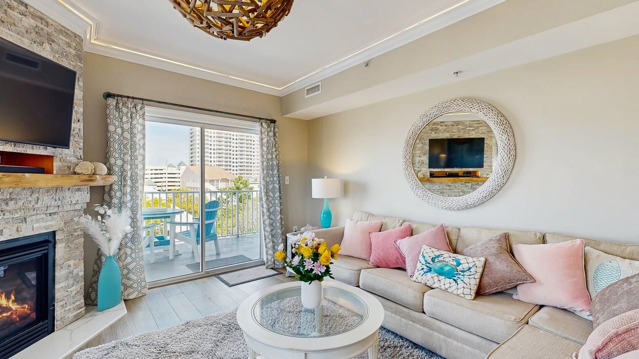 Un salon avec une cheminée, un téléviseur, un canapé et un balcon offrant une vue sur les immeubles.