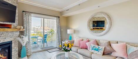 Un salon avec une cheminée, un téléviseur, un canapé et un balcon offrant une vue sur les immeubles.