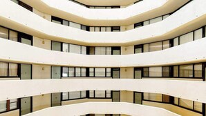 Ein mehrgeschossiges Interieur mit einem offenen Innenhof, mehreren Balkonen und einem modernen architektonischen Design.