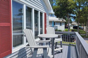 A deck with two Adirondack chairs and a small table, overlooking a residential area. - Inviting home near beaches with fast WiFi, AC, full kitchen & W/D - dog-friendly (Ocean City)