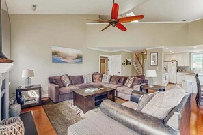 A living room with a sectional sofa, a coffee table, a fireplace, and a ceiling fan.