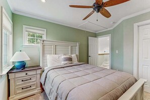 A bedroom with a bed, nightstand, lamp, and ceiling fan.