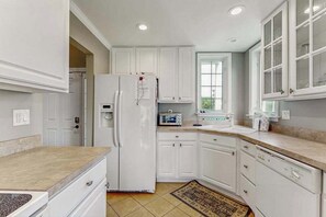 A kitchen with white cabinets, a refrigerator, a toaster, and a window.