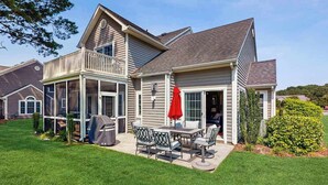 A two-story house with a covered patio, a grill, and a red umbrella. - 4BR Coastal Getaway - Golf, Pool & OC Beach access in Berlin, MD (Berlin)