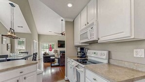 A modern kitchen with white cabinetry, a built-in microwave, and a stove. - 4BR Coastal Getaway - Golf, Pool & OC Beach access in Berlin, MD (Berlin)