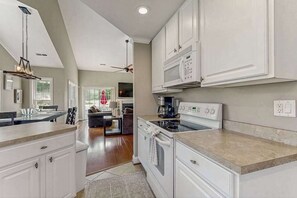 A modern kitchen with white cabinetry, a built-in microwave, and a stove.