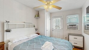 A bedroom with a bed, a ceiling fan, a window with blinds, an air conditioning unit, and a door. - Spacious ocean view condo with large balcony & washer/dryer - easy beach access (Ocean City)