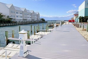 A wooden pier leading to a dock with boats, a lighthouse, and a row of buildings with a clear view of the water. - Sunset Island - 57 Island Edge (Ocean City)