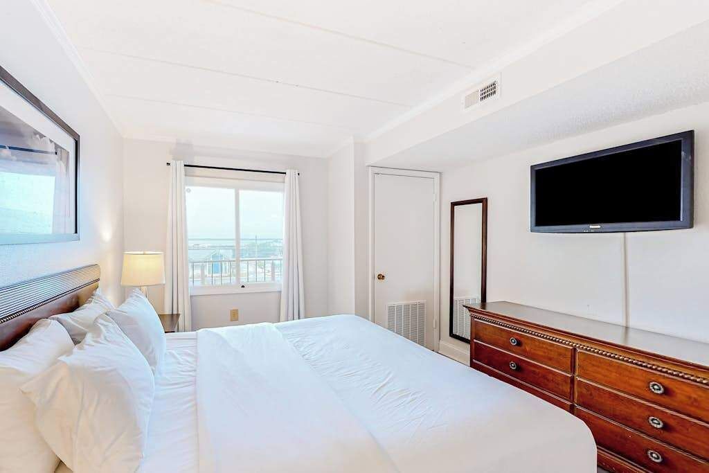 Una habitación de hotel con cama, cómoda, televisor y ventana con vistas.