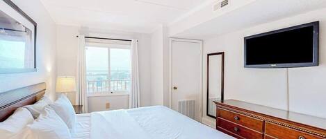 Una habitación de hotel con cama, cómoda, televisor y ventana con vistas.