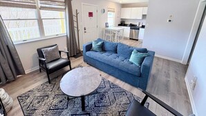 Una sala de estar moderna con un sofá, una mesa de centro y un comedor con una cocina al fondo.