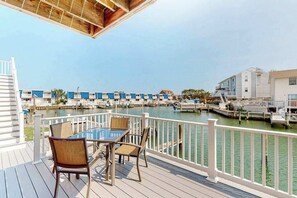 A deck with a table and chairs, overlooking a marina with boats and docked yachts. - Bayshore 603A (Ocean City)