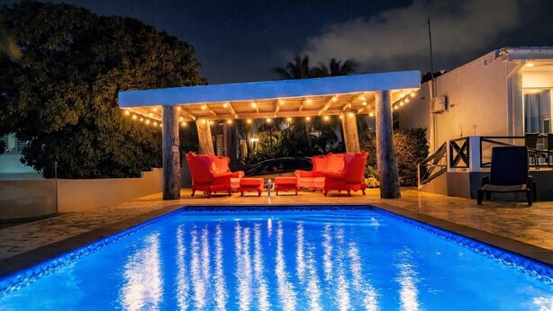 Uma piscina com área de estar coberta e luzes de corda.