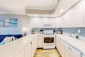 A modern kitchen with white cabinetry, a microwave, an oven, and a tiled backsplash. - Oceanfront, 2nd-floor condo with gorgeous view, balcony, pool & great location (Ocean City)