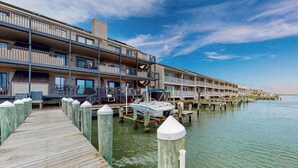 A waterfront hotel with multiple balconies, a dock, and a boat. - Bahama Princess I (Ocean City)