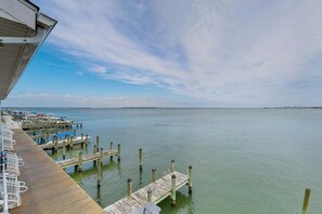 Une propriété située au bord de l’eau, avec une jetée en bois s’étendant sur une étendue d’eau calme, un ciel dégagé et une côte lointaine.