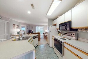 Cocina compacta con microondas, estufa y lavabo. Hay un comedor con mesa y sillas.