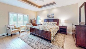 A bedroom with a large bed, a ceiling fan, a window with blinds, a nightstand, a dresser, and a painting on the wall. - Turtle Shores-22 Boston (Ocean Pines)