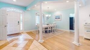 A dining area with a white table and chairs, a chandelier, and a view into the kitchen. - Turtle Shores-22 Boston (Ocean Pines)