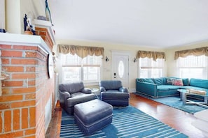 Ein Wohnzimmer mit Kamin aus Backstein, zwei Sofas und einem blau gestreiften Teppich.