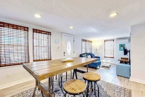 A modern living room with a wooden dining table, blue sofa, and a small coffee table.