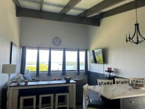 Un comedor con una mesa y sillas, un reloj en la pared y una ventana con vistas.
