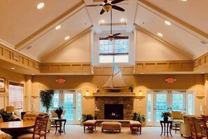 Eine geräumige Lobby mit hoher Decke, Kamin, Sitzbereich und großem Fenster.