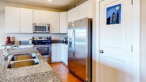 A kitchen with white cabinets, stainless steel appliances, granite countertops, and a sink. - Seaside Village Bowline 13007 -2 (West Ocean City)