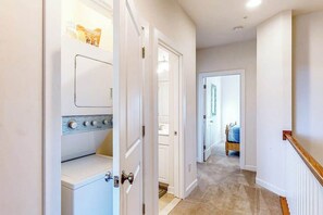 A hallway with a laundry room, a bedroom, and a door leading to another room. - Seaside Village Bowline  13007 -2 (West Ocean City)