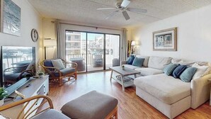 A living room with a sofa, armchairs, a coffee table, a TV, and a ceiling fan. - Dog-friendly 1st-floor end condo with beach entrance view - steps to the beach (Ocean City)