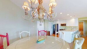 A dining area with a round table, chairs, and a chandelier. - Waterfront escape with two pools, outdoor shower, balcony, WiFi & central AC (Ocean City)