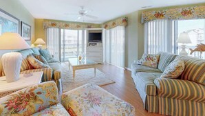 A living room with a sofa, armchair, coffee table, and a television. - Waterfront escape with two pools, outdoor shower, balcony, WiFi & central AC (Ocean City)