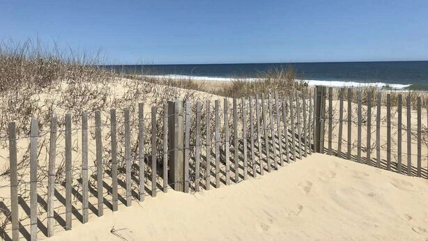 A sandy beach with a wooden fence and a clear blue sky. - Waterfront escape with two pools, outdoor shower, balcony, WiFi & central AC (Ocean City)