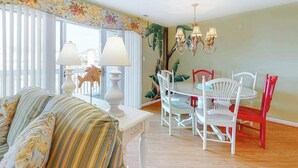 A dining area with a table and chairs, a sofa, and a chandelier. - Waterfront escape with two pools, outdoor shower, balcony, WiFi & central AC (Ocean City)