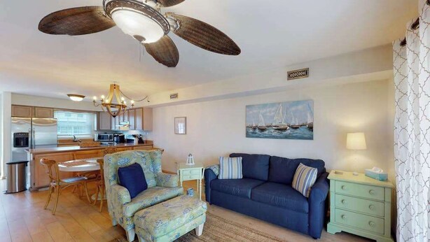 Ein Wohnzimmer mit einer Couch, einem Hocker und einem Essbereich mit Stühlen und einem Tisch.